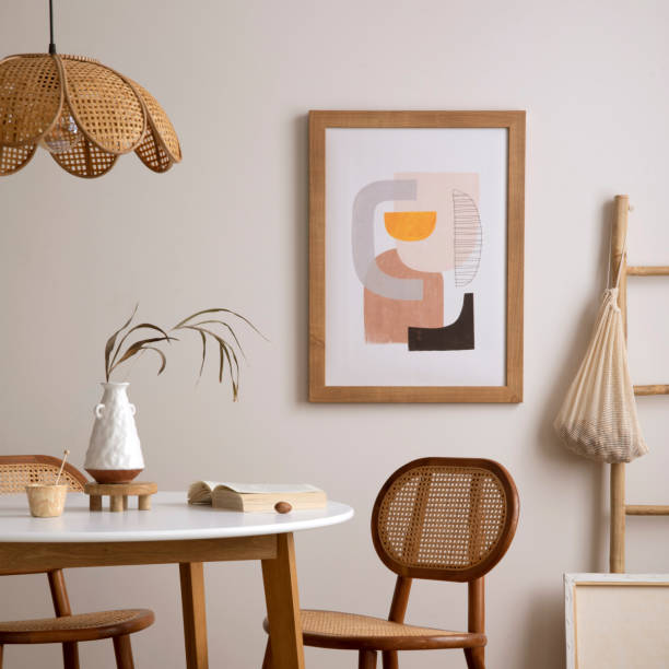 istock Creative composition of dining room interior with round table, rattan chair, wooden commode, pock up poster and kitchen accessories. Beige wall with mock up poster. Home decor. Template. 1646220414