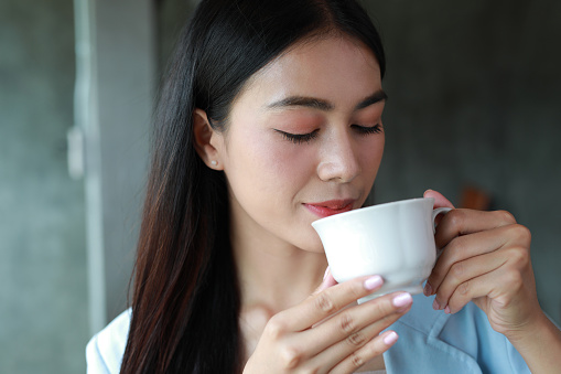 Close up of beautiful woman drinking coffee or tea in a cafe.