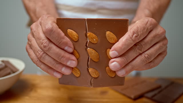 SLO MO LD Hands of an older person breaking a chocolate in half