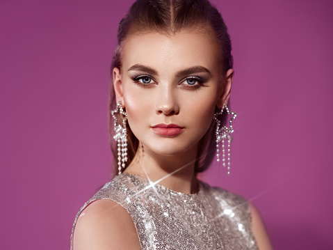 Portrait beautiful woman with jewelry. Beauty fashion. Eyelashes. Cosmetic eyeshadow. Care and beauty hair products. Model in a silver dress