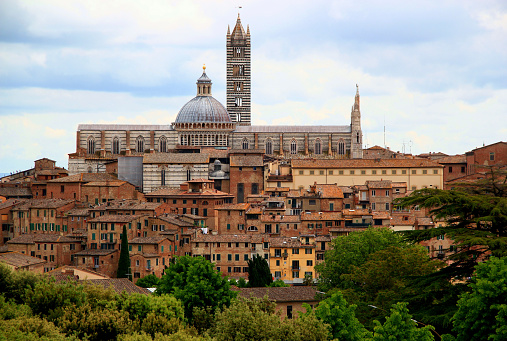 Panoramic view of the historic part of the city of Siena with the Duomo di Siena against a stormy sky in the Tuscany region of Italy