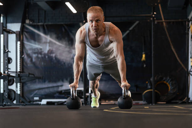istock Fit and muscular man doing horizontal push-ups on dumbbells in gym. 1646245201