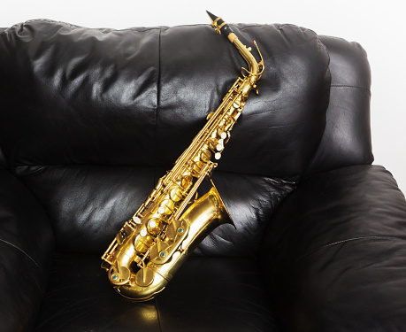 6 years old boy plays saxophone at studio, side view