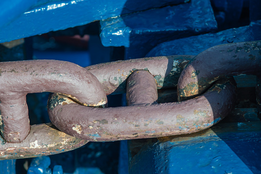 A piece of a huge steel anchor chain of a large ship, strong iron forged links, industrial design, practical purpose, interesting background, deck fragment, vintage look.