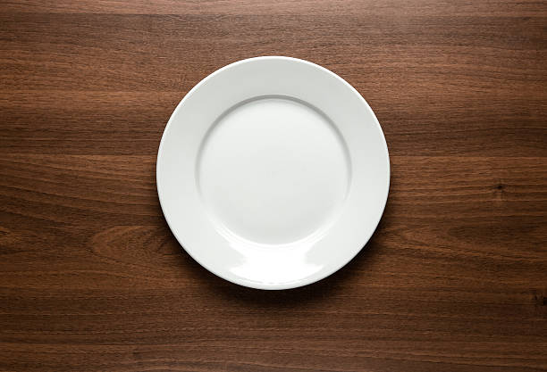 White empty plate at the table Close up of white empty plate at the wooden table with copy space place setting table plate dining table stock pictures, royalty-free photos & images