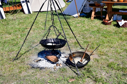 A close up on some bread baked on a metal or brass pan hanging from a special metal frame seen in the middle of a medieval camp spotted on a sunny summer day during a historical reenactment