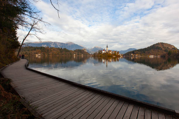 bled lake reflections and julian alps in the spring season photo, radovljica bled, slovenia - julian alps mountain lake reflection imagens e fotografias de stock