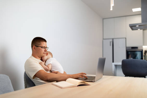 istock Father holding baby and working on laptop 1646305908