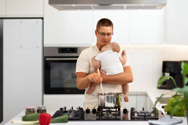 istock Father holding a baby and cooking meal 1646306910