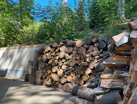 Selective focus on a stack of firewood for heating outdoors near a brick wall. The concept of cutting and storing firewood