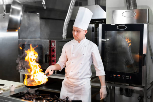 istock Chef cooking with flame in a frying pan on a kitchen stove. 1646350537