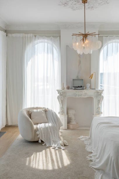 istock a gentle cozy bright apartment with huge panoramic windows with sunlight. bedroom in soft beige tones with a fireplace and a comfortable stylish upholstered armchair and bed 1646357728