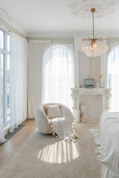 istock a gentle cozy bright apartment with huge panoramic windows with sunlight. bedroom in soft beige tones with a fireplace and a comfortable stylish upholstered armchair and bed 1646357759