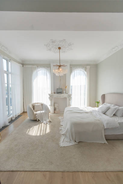 istock a gentle cozy bright apartment with huge panoramic windows with sunlight. bedroom in soft beige tones with a fireplace and a comfortable stylish upholstered armchair and bed 1646358321