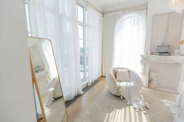 istock a gentle cozy bright apartment with huge panoramic windows with sunlight. bedroom in soft beige tones with a fireplace and a comfortable stylish upholstered armchair and bed 1646358325