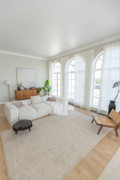 istock cozy bright apartment with huge panoramic windows with sunlight. bedroom in white and beige tones with fireplace and soft armchair. stylish living room with log coffee table and large white sofa 1646358385