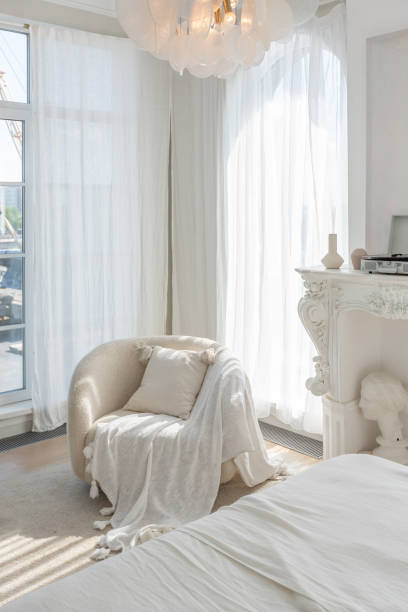 istock a gentle cozy bright apartment with huge panoramic windows with sunlight. bedroom in soft beige tones with a fireplace and a comfortable stylish upholstered armchair and bed 1646358386