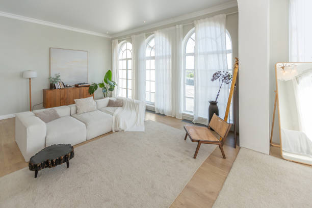 istock cozy bright apartment with huge panoramic windows with sunlight. bedroom in white and beige tones with fireplace and soft armchair. stylish living room with log coffee table and large white sofa 1646358544