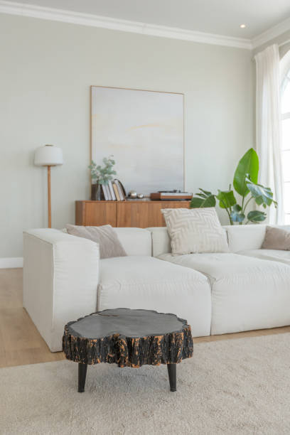 istock cozy bright apartment with huge panoramic windows with sunlight. bedroom in white and beige tones with fireplace and soft armchair. stylish living room with log coffee table and large white sofa 1646358898