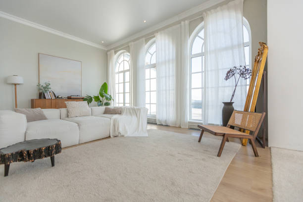 istock cozy bright apartment with huge panoramic windows with sunlight. bedroom in white and beige tones with fireplace and soft armchair. stylish living room with log coffee table and large white sofa 1646358906