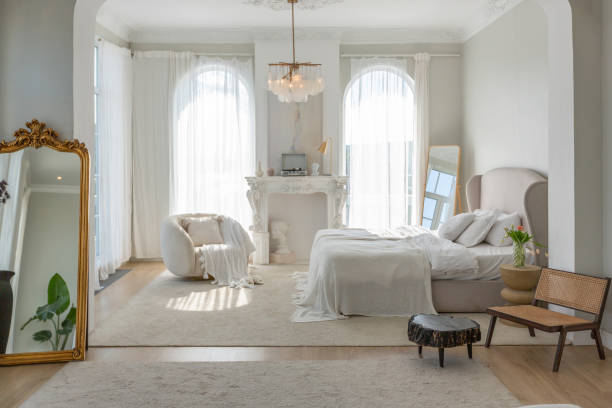 istock a gentle cozy bright apartment with huge panoramic windows with sunlight. bedroom in soft beige tones with a fireplace and a comfortable stylish upholstered armchair and bed 1646360602