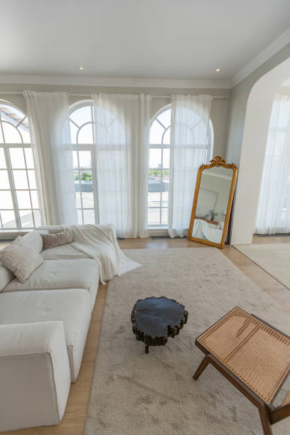 istock cozy bright apartment with huge panoramic windows with sunlight. bedroom in white and beige tones with fireplace and soft armchair. stylish living room with log coffee table and large white sofa 1646360809