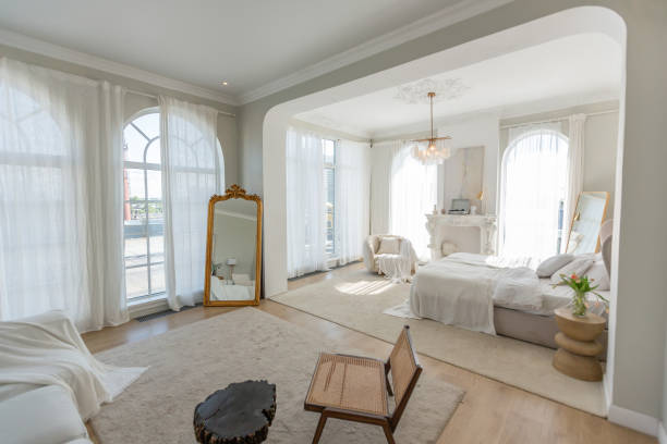 istock cozy bright apartment with huge panoramic windows with sunlight. bedroom in white and beige tones with fireplace and soft armchair. stylish living room with log coffee table and large white sofa 1646360961