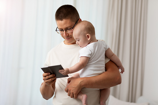 Father holding baby and using tablet