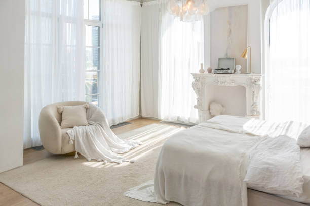 istock cozy bright apartment with huge panoramic windows with sunlight. bedroom in white and beige tones with fireplace and soft armchair. stylish living room with log coffee table and large white sofa 1646361182
