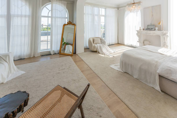 istock cozy bright apartment with huge panoramic windows with sunlight. bedroom in white and beige tones with fireplace and soft armchair. stylish living room with log coffee table and large white sofa 1646361194