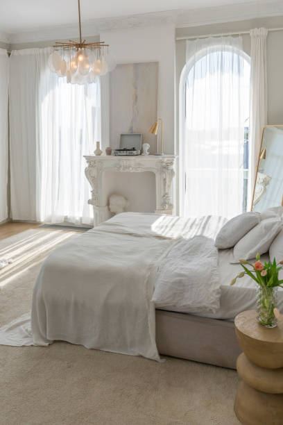 istock a gentle cozy bright apartment with huge panoramic windows with sunlight. bedroom in soft beige tones with a fireplace and a comfortable stylish upholstered armchair and bed 1646361195