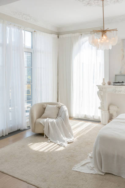 istock a gentle cozy bright apartment with huge panoramic windows with sunlight. bedroom in soft beige tones with a fireplace and a comfortable stylish upholstered armchair and bed 1646361207