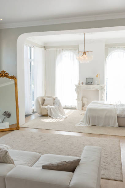 istock cozy bright apartment with huge panoramic windows with sunlight. bedroom in white and beige tones with fireplace and soft armchair. stylish living room with log coffee table and large white sofa 1646362306