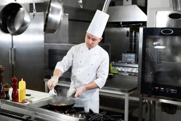 istock Chef roasts prawns in a frying pan. 1646368517