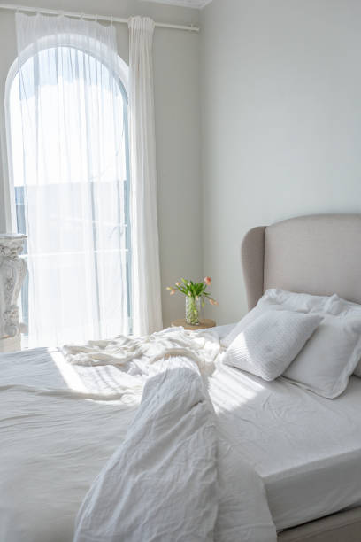 istock a gentle cozy bright apartment with huge panoramic windows with sunlight. bedroom in soft beige tones with a fireplace and a comfortable stylish upholstered armchair and bed 1646368549