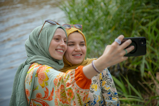 Young beautiful girlfriends taking selfie while outing in nature