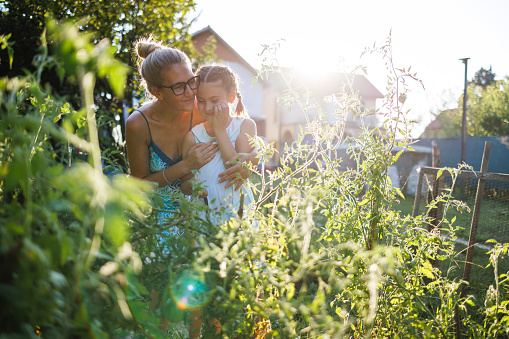Woman embraces daughter in vegetable garden