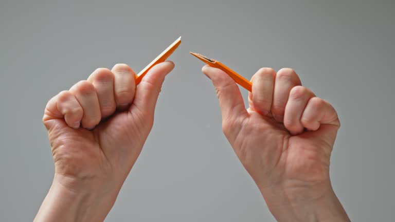 SLO MO LD Hands breaking a pencil