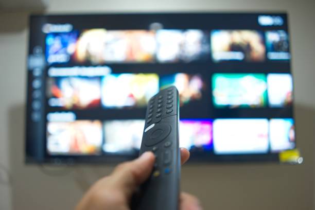 istock Hand with TV remote control, switching TV series from streaming service platform. The new way of enjoying entertainment at home. 1646376566
