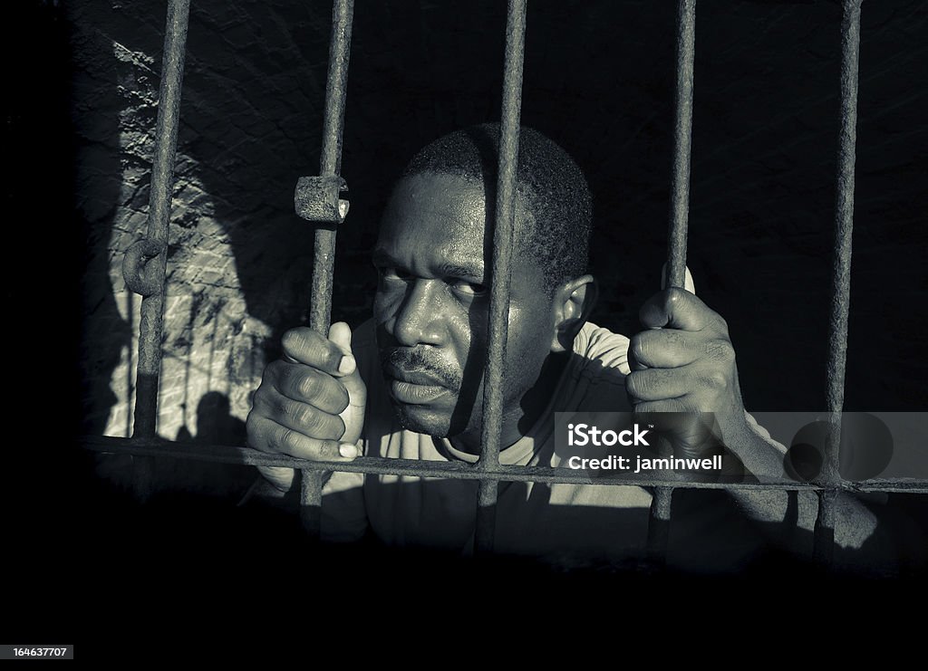 Mentales disburbed mirando hombre por detrás de barras de celda de prisión - Foto de stock de Cárcel libre de derechos