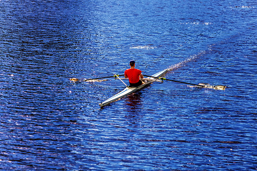 Cambridge, Massachusetts, USA - August 19, 2023: Male rower in a single scull boat on the Charles River.