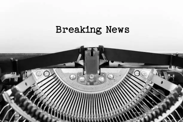 Photo of Breaking news phrase closeup being typing and centered on a sheet of paper on old vintage typewriter mechanical