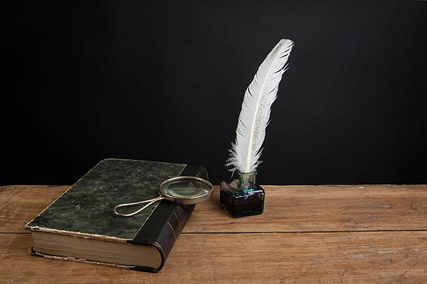 istock Quill, inkwell, old book and magnifying glass on wood table 164641601