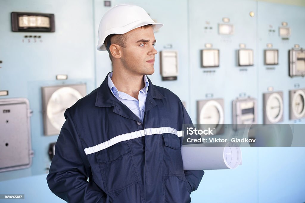 Ingeniero con casco y blueprints en la sala de control - Foto de stock de Accesorio de cabeza libre de derechos