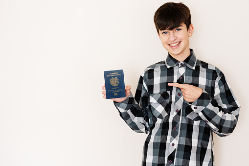 Young teenager boy holding Armenia passport looking positive and happy standing and smiling with a confident smile against white background.
