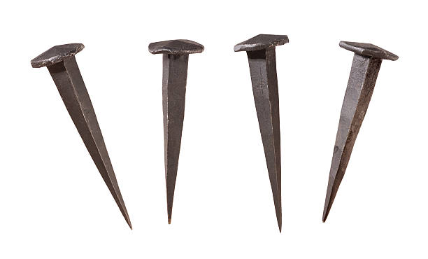Antique Handmade Nails Four Antique Handmade Nails Displayed at different angles.  The metal nails are dark in color, and show a flat head coming to a sharp point at the end.  These are the kind of nails that were used by the pioneers to build log cabins. The image is isolated on a white background, and includes a clipping path. spiked stock pictures, royalty-free photos & images