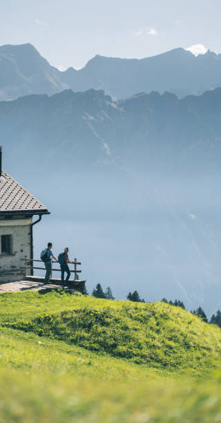They lean against the railing above the valley below