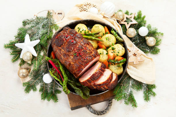 istock Roasted sliced Christmas ham on plate with vegetables, festive decoration. 1646453082