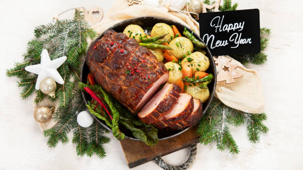 istock Roasted sliced Christmas ham on plate with vegetables, festive decoration. 1646462029