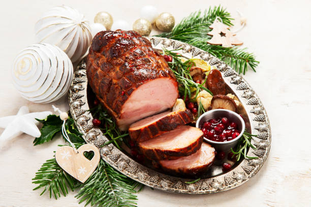 istock Roasted sliced Christmas ham on plate with vegetables, festive decoration. 1646467676